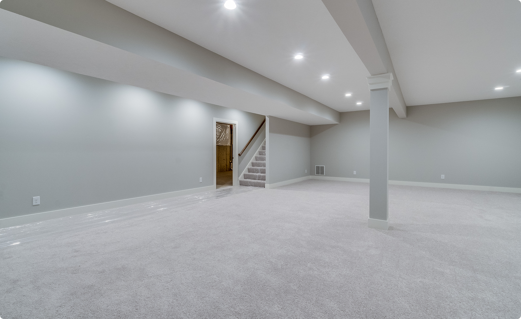 Empty finished basement with stairs and recessed lighting.
